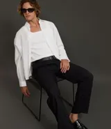 Pantalón de sastrería de corte recto, color negro con finas rayas verticales blancas. Presenta pliegues frontales, cintura ancha con trabillas para cinturón y cierre tradicional.