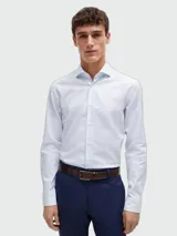 Camisa BOSS de manga larga en color blanco con sutil estampado de lunares celestes, cuello camisero clásico y cierre frontal de botones.