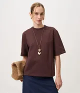 Remera boxy de manga corta y cuello redondo, confeccionada en mezcla de algodón, poliéster y elastano. Presenta un diseño liso de corte recto y holgado.