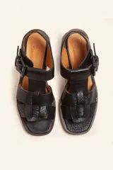 Sandalia de cuero vacuno texturado color negro, con tiras anchas y hebilla lateral. Taco ancho de madera.