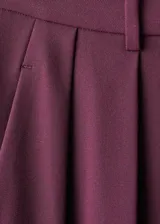Pantalón de vestir bordó de tiro medio, con diseño wide leg, pinzas en la parte delantera, bolsillos laterales y cierre frontal con botón, gancho y cremallera.