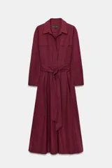 Vestido midi de estilo camisero color bordó, con cuello solapa, escote en pico y cierre frontal con botones ocultos. Presenta manga larga, bolsillos laterales ocultos, solapas decorativas en el pecho y cinturón de lazada en el mismo tejido.