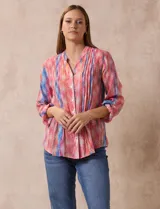 Blusa de gasa estampada multicolor, marca Ruby Rd. Tiene cuello a la base, escote en V, abertura central con botones y plisados en la parte delantera. Las mangas son 3/4 y tienen un largo regulable con presilla y botón.