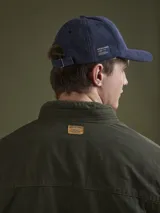 Campera de algodón color azul marino con cuello alto, cierre frontal con cremallera y botones a presión, cuatro bolsillos frontales con solapa y puños con botón.