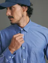 Camisa de vestir de corte clásico, color azul, con cuello italiano, cierre frontal de botones y bolsillo en el pecho.