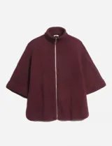 Poncho tejido color bordó con cuello alto y cierre frontal completo. Presenta mangas cortas con terminación en puño acanalado y un diseño holgado.