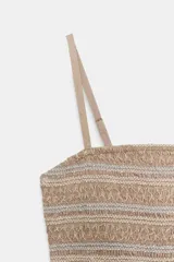 Vestido midi color beige, con cuerpo ajustado de nido de abeja elástico con bordados a contraste y falda larga en capas. Presenta escote recto y tirantes finos ajustables.