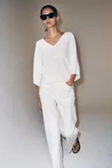 Top de punto fluido color negro, con escote en V y mangas cortas amplias.