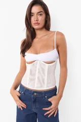 Corset blanco de microtul en el cuerpo y microfibra en el busto, con sustracción debajo del busto y frunce. Tiene ganchos lenceros en la espalda, ballenas con refuerzo en los recortes y terminaciones con elástico.