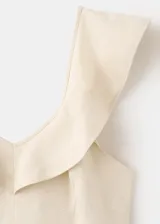 Vestido midi de mezcla de lino y viscosa en color beige, con diseño evasé, cuello en V con volantes decorativos, tirantes anchos y cierre de cremallera lateral.