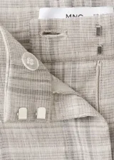 Pantalón de tiro medio con diseño recto y largo, con detalle de pinzas y estampado a cuadros. Cuenta con trabillas en la cintura, dos bolsillos laterales y cierre oculto de botón, gancho y cremallera.
