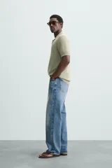 Polo de manga corta color verde azulado oscuro, confeccionado en tejido de punto con textura. Presenta cuello solapa y cierre frontal de botonadura.