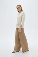 Sweater acrílico en tono natural, de corte holgado, con cuello a la base decorado con sutiles volados, mangas 3/4 y diseño tejido con motivos geométricos calados en el frente.