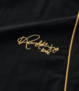 Pantalón deportivo de microfibra color negro, con corte holgado y diseño de piping contrastante en color amarillo. Cuenta con cintura elástica con cordón de ajuste, bolsillos laterales y logo bordado.