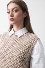 Chaleco tejido de algodón y acrílico, color rojo y blanco con patrón geométrico. Tiene cuello redondo y bordes acanalados en rojo.