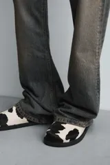 Zueco de piel con pelo con estampado de vaca en blanco y negro. Presenta una horma redonda y una suela de goma negra con volumen.