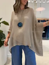 Poncho de tejido de punto abierto y ligero, color visón, con cuello redondo y diseño holgado de mangas amplias.