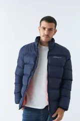 Campera puffer color bordó, con cuello alto y cierre frontal. Tiene bolsillos laterales con cierre y logo estampado en el pecho.