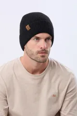 Gorro tejido de punto acanalado en color azul marino, con vuelta y etiqueta decorativa de cuero sintético en el lateral.