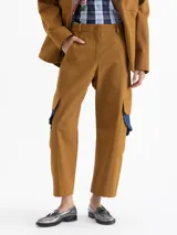 Pantalón de gabardina color marrón, de tiro alto y silueta estructurada. Cuenta con volados de denim azul aplicados sobre los bolsillos plaqué laterales y bolsillos plaqué traseros con remache dorado.