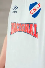 Musculosa de básquet Umbro del Club Nacional de Football, modelo alternativa 2025. Diseño en color azul marino con patrón sutil estampado, cuello redondo y sisas en rib con líneas blancas y rojas. Incluye el logo de Umbro, el escudo del club y la inscripción "Nacional" en el frente.