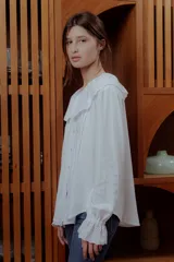 Camisa blanca de lino con cuello babero de broderie y mangas largas.