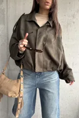 Campera tipo bomber de gamuza color verde, con diseño oversize, cuello camisero, cierre frontal y detalles de charreteras en los hombros.