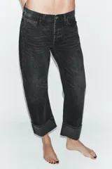 Jeans rectos de tiro medio en denim negro con efecto lavado. Presenta diseño de cinco bolsillos, trabillas para cinto y bajo con vuelta marcada. Cierre frontal con botones metálicos ocultos.