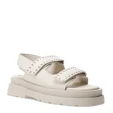 Sandalias chunky de color marfil con plataforma y suela dentada. Presentan dos tiras frontales anchas con cierre de velcro decoradas con pequeños tachas doradas, y una tira trasera ajustable.