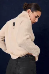 Polera de tejido suave con textura, cuello alto, mangas largas y silueta recta.