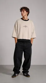 Buzo de corte oversize con mangas tres cuartos, confeccionado en tela color beige con cuello y ruedo en contraste color negro. Presenta un pequeño estampado tipográfico en el centro del pecho.