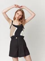 Short color beige de lino con tiro alto, elástico en la pretina trasera, cierre delantero con botón, tablas en el frente, bolsillos delanteros y dobladillo invisible.