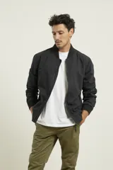 Campera tipo bomber color negro, 100% algodón, con puños tejidos al tono y cierres metálicos.