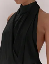 Top negro con escote halter y cuello alto. Presenta un diseño cruzado en el frente con pliegues, espalda descubierta con lazo regulable y bajo con terminación elástica.