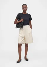 Remera blanca de algodón con corte boxy, ligeramente oversize, de líneas rectas y mangas cortas, con cuello redondo acanalado.