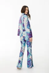 Pantalón de vestir con leve evasé y tajo en laterales, con estampado de flores grandes en tonos violeta y naranja.