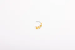 Anillo artesanal de vidrio transparente con diseño irregular y pequeñas esferas de color miel incrustadas.