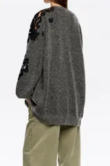 Cardigan largo de punto oversize en color gris, con escote en pico y cierre frontal de botones. Presenta mangas largas con volumen y detalles de encaje negro a contraste en hombros y mangas.