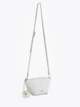 Bandolera de cuero vacuno con silueta estructurada, cierre superior y aplique metálico frontal. Incluye correa regulable y tag colgante con detalle decorativo.