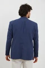 Saco azul de lino, de corte clásico, con solapa de muesca, cierre de dos botones, bolsillos frontales con solapa y aberturas traseras.