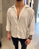 Camisa de fibrana color beige de corte relajado, con mangas largas y cuello clásico.