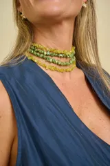 Collar tipo choker compuesto por múltiples tiras de cuentas de piedras irregulares en tonos verde y amarillo.