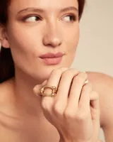 Anillo dorado con diseño abstracto de líneas curvas y esferas.