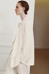 Blazer cruzado Zara Woman Collection confeccionado en hilatura de viscosa, de color blanco. Presenta cuello alto, manga larga con abertura y botones, bolsillos delanteros y cierre frontal cruzado con botones.