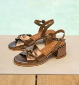 Sandalias de cuero color dorado, con plataforma y taco cuadrado. Presentan tiras cruzadas en el empeine y pulsera al tobillo con hebilla.