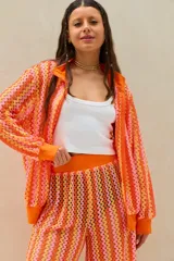 Conjunto de dos piezas tejido a crochet con diseño de ondas en tonos naranja, rosado y amarillo, compuesto por una camisa de manga larga y un pantalón largo de corte recto.