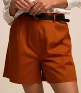 Short de vestir color beige, con cintura alta, pliegues frontales, cinturón de cuero sintético con hebilla metálica y cierre frontal con botón y cremallera.