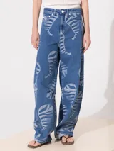 Pantalón de jean azul con estampado de siluetas de animales en color gris, de corte slouchy, tiro alto y piernas anchas que se angostan hacia el tobillo.