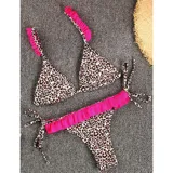 Bikini de dos piezas con estampado animal print. El top es de estilo triángulo con breteles decorados con volados fucsias. La bombacha es tipo tanga con laterales atados y un detalle de volado fucsia en la parte frontal.