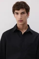 Camisa negra de manga larga con cuello clásico, tapeta con botones y bolsillo en el pecho. Corte regular.